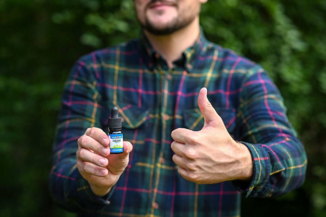 Un bărbat ține un flacon de 10 ml de ulei CBD Formula Swiss în ulei de semințe de cânepă