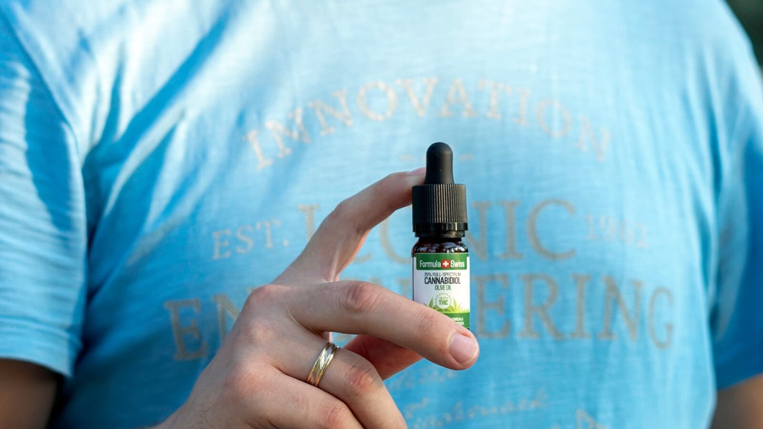O mână care ține un flacon de 10 ml de ulei CBD Formula Swiss în ulei de măsline