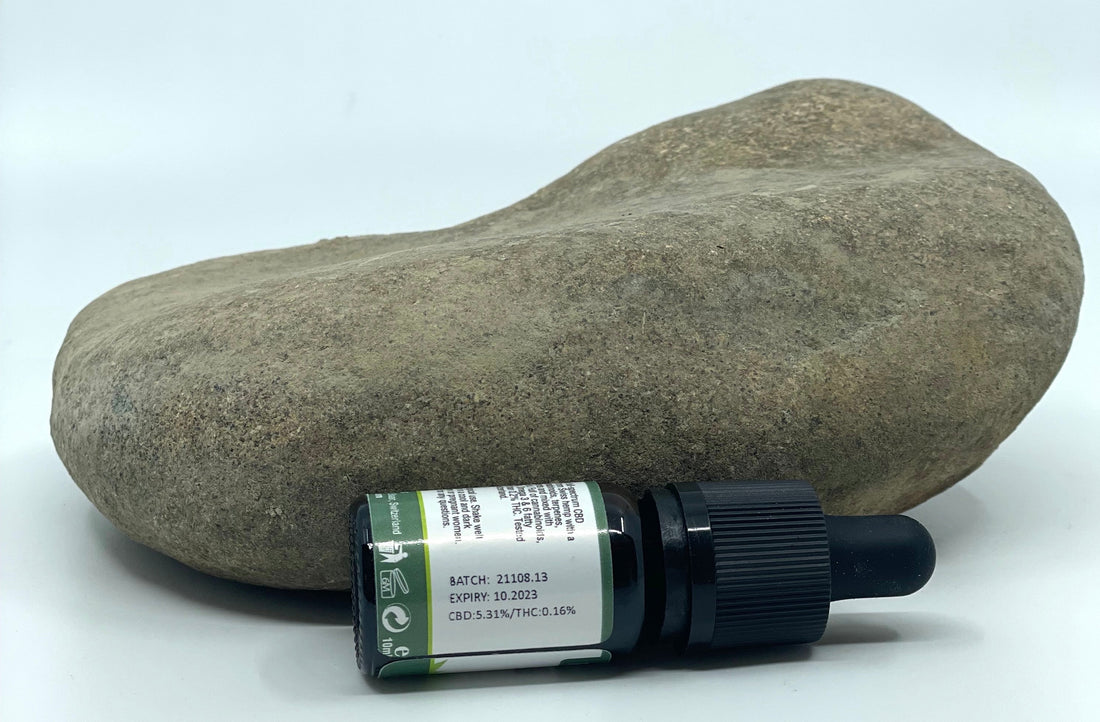 Ulei CBD cu spectru complet Formula Swiss de 10 ml lângă o piatră, cu eticheta lotului: CBD 5,31% și THC 0,16%
