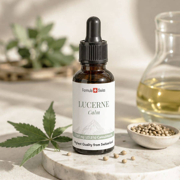 Flaconul cu ulei de canabinoizi Formula Swiss Lucerne Calm, expus alături de frunze și semințe de cânepă și ulei auriu, într-un decor natural luminos.