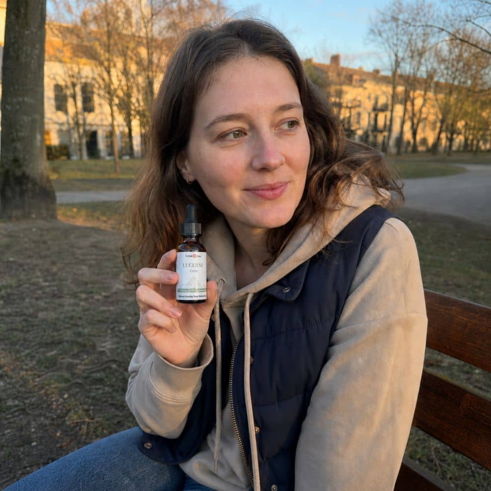 Femeie care ține un flacon de ulei CBD Lucerne în aer liber, într-un parc